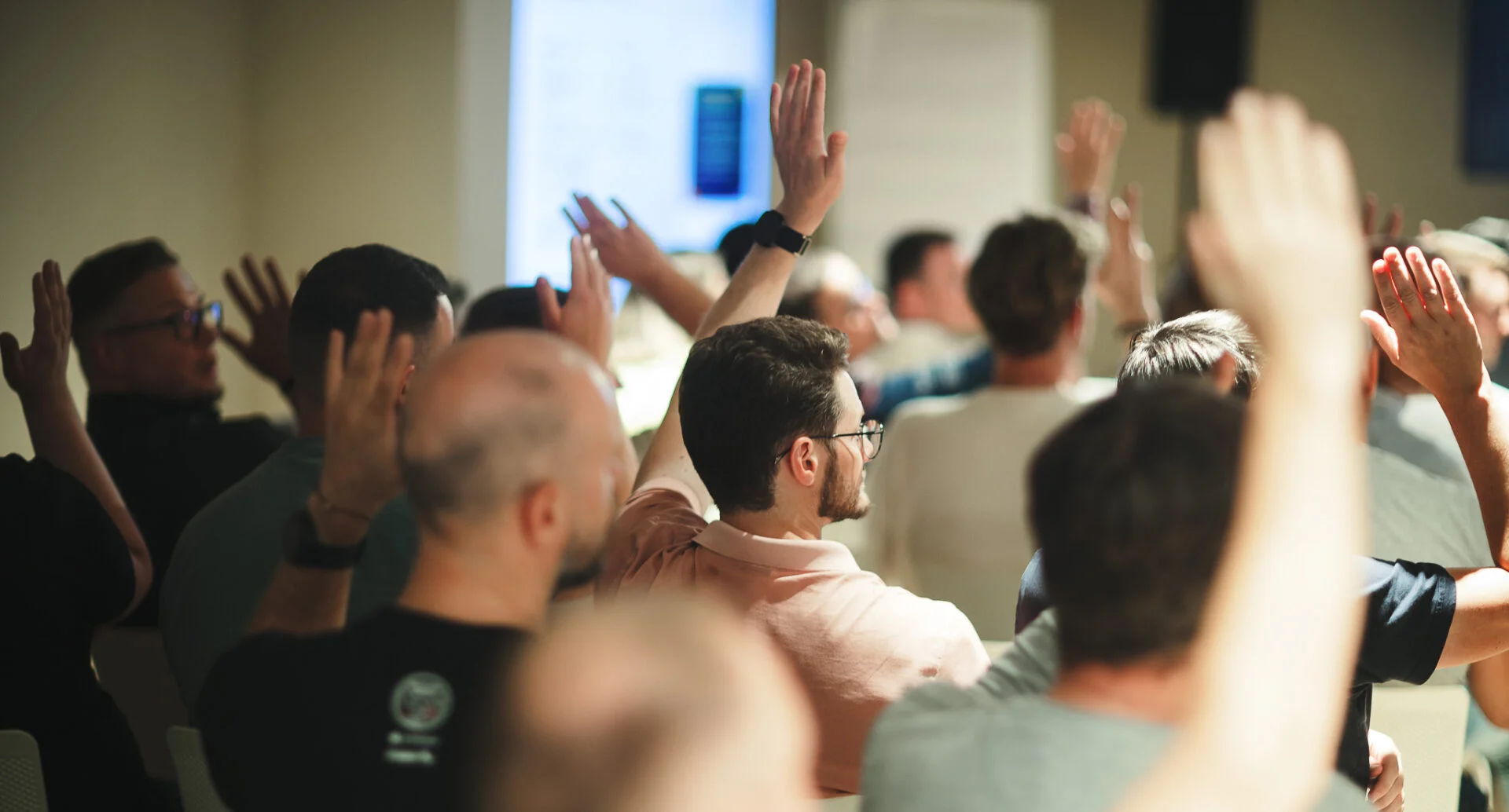 Photo of CUJO AI employees sitting in a conference with hands raised